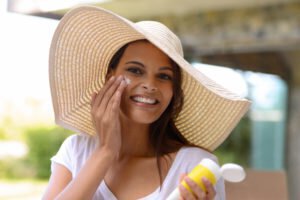 Woman wearing a sun hat using skin care product